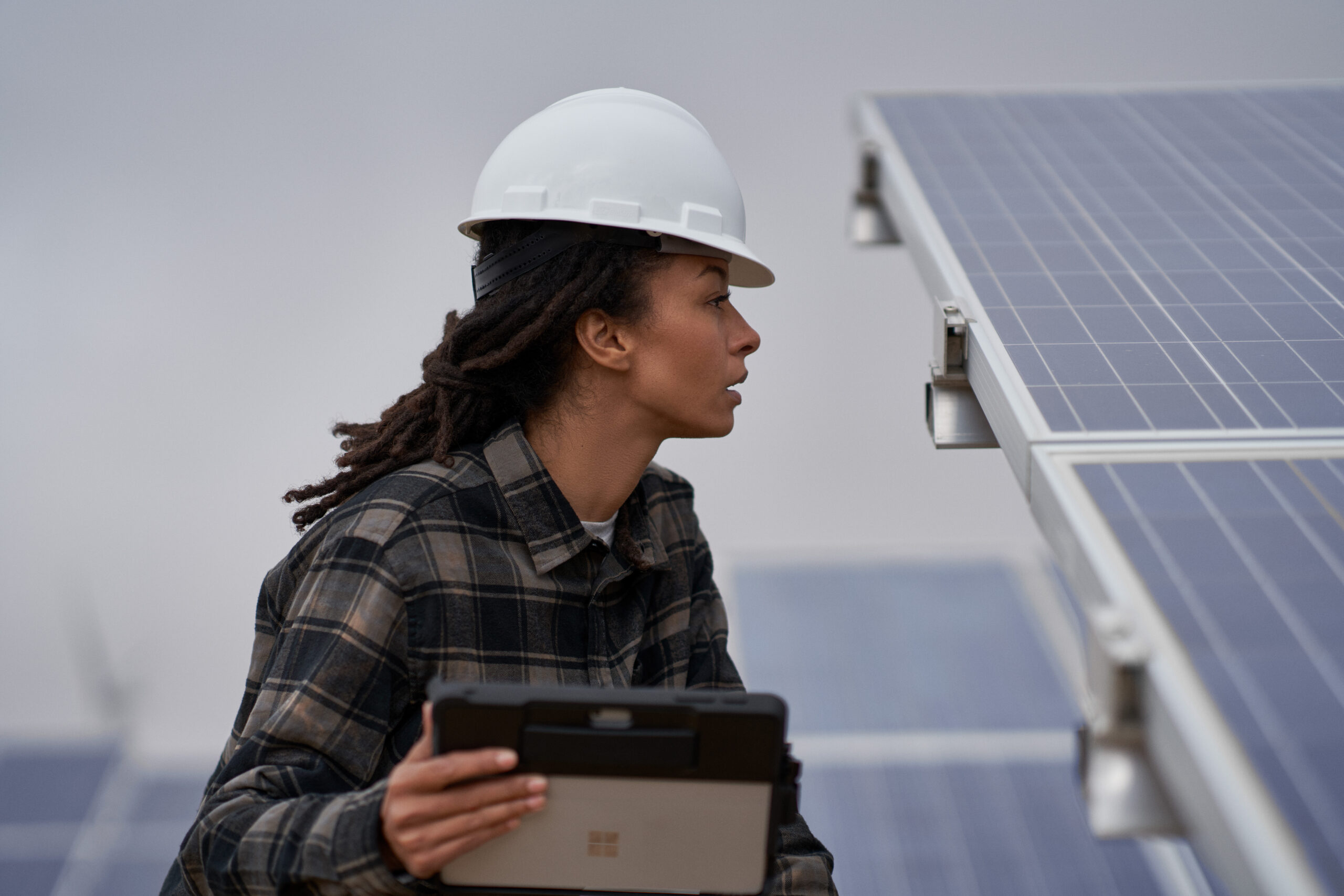 Photo of a female field engineer using a self-service bot to get help inspecting solar panels on a wind farm