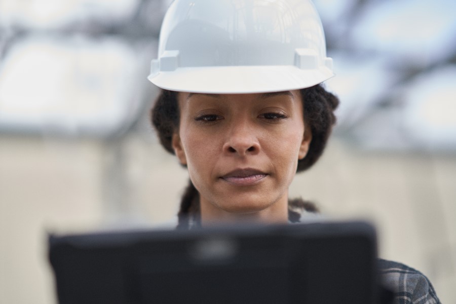 Field engineer wearing hard hat looking at laptop screen