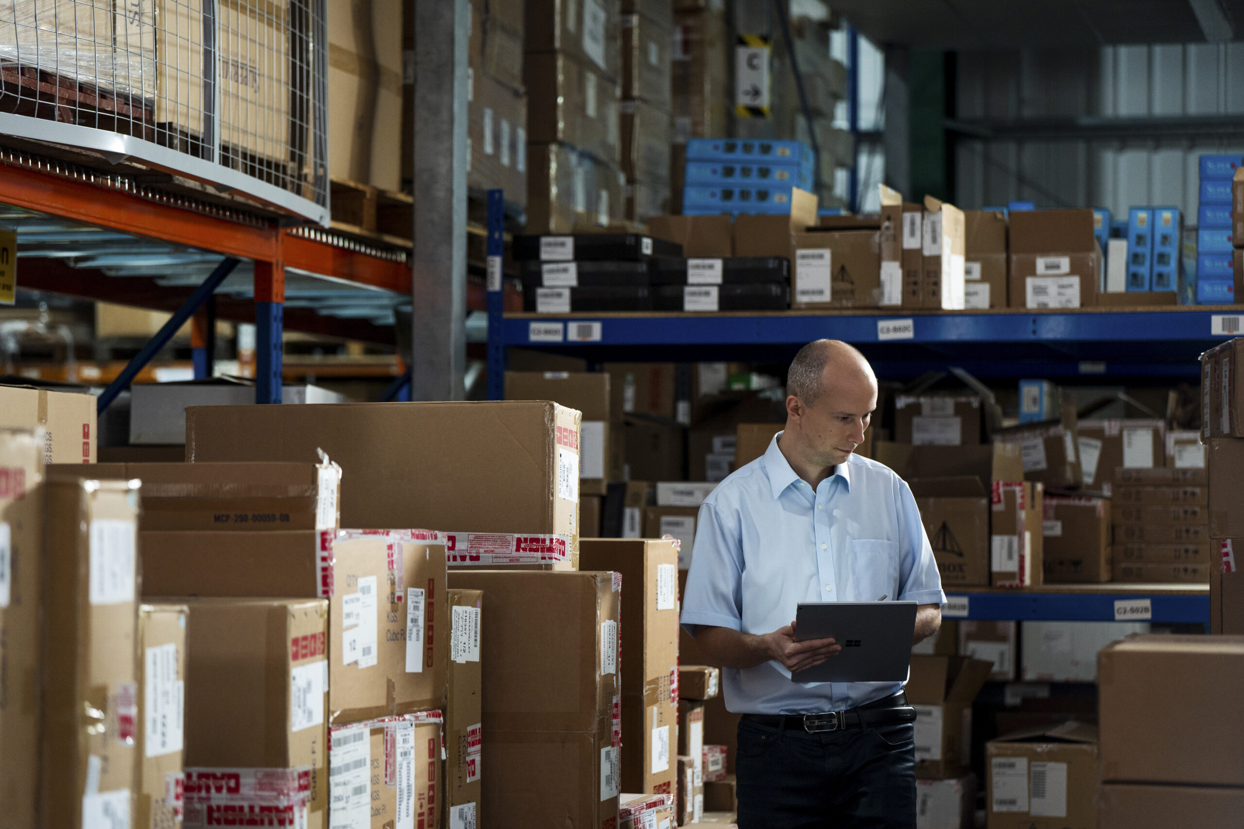 Photo of a man in a warehouse using Microsoft Dynamics 365 Supply Chain Management Warehouse management on a tablet