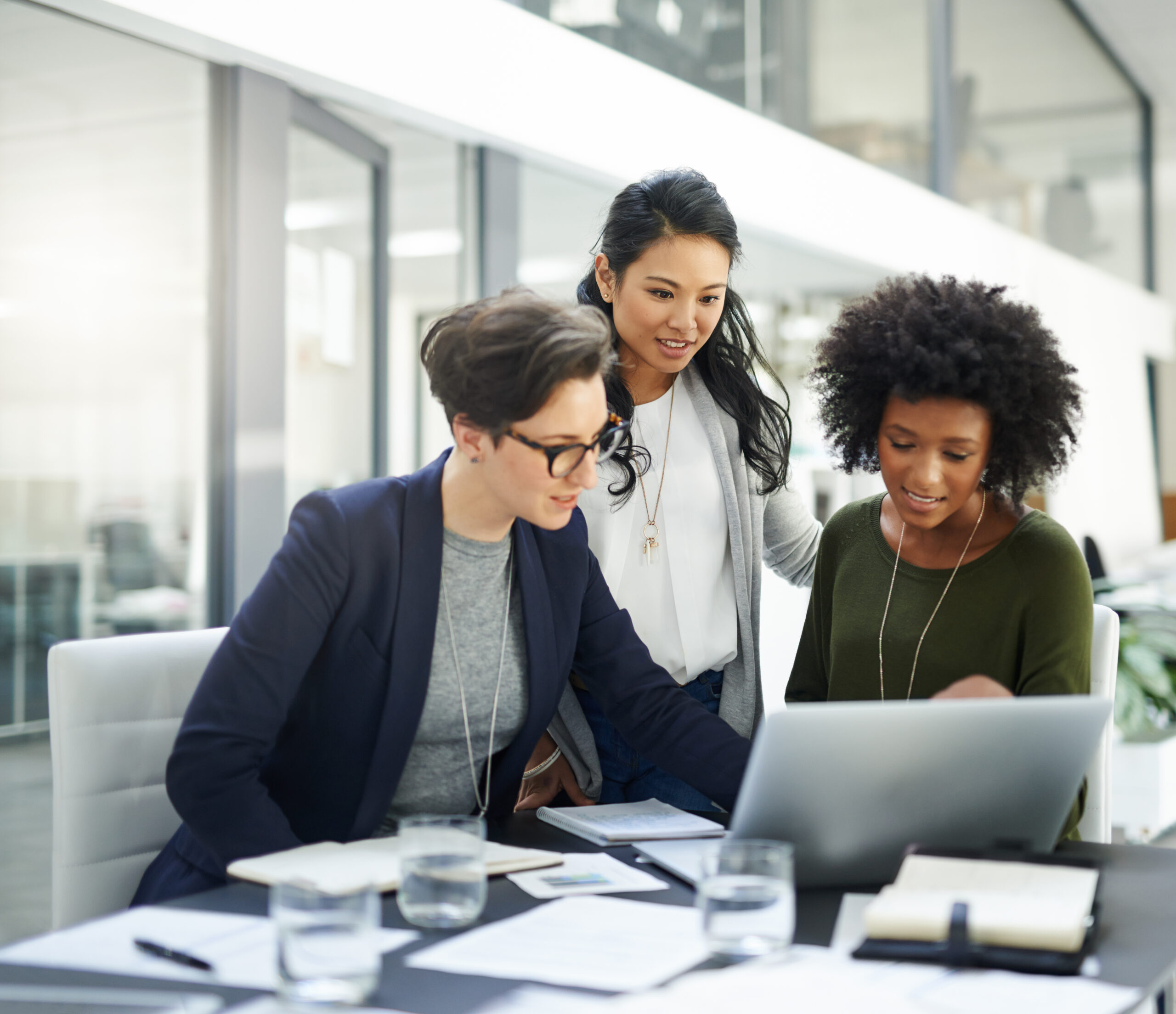 Photo of three businesswomen working at a laptop computer