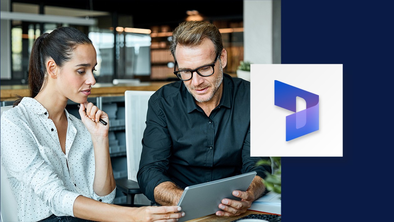 A man and woman sitting at a table, looking at a tablet. Navy blue borders the right side of the image, overlaid with the Dynamics 365 logo