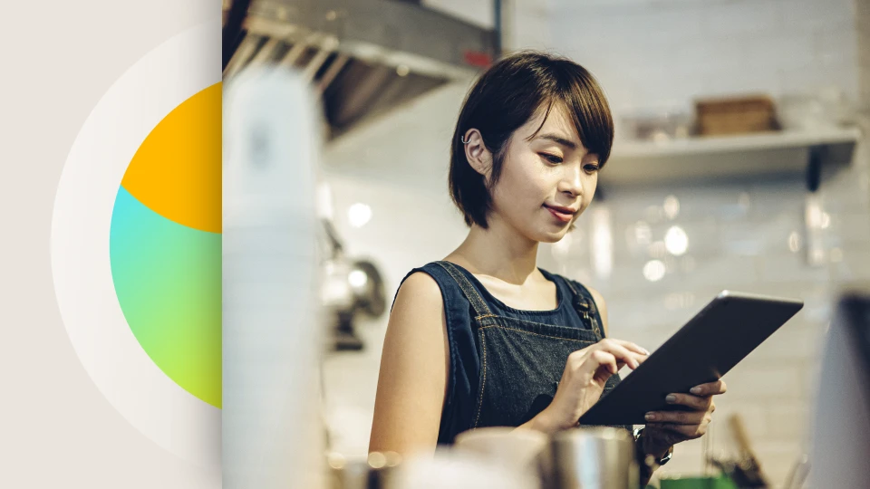 A female retail employee works on a tablet in her shop