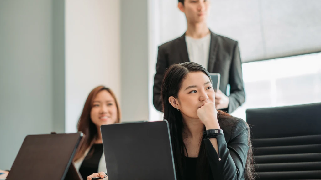 Team collaboration in a modern office meeting, with professionals reviewing insights and discussing strategy using laptops during a business session.