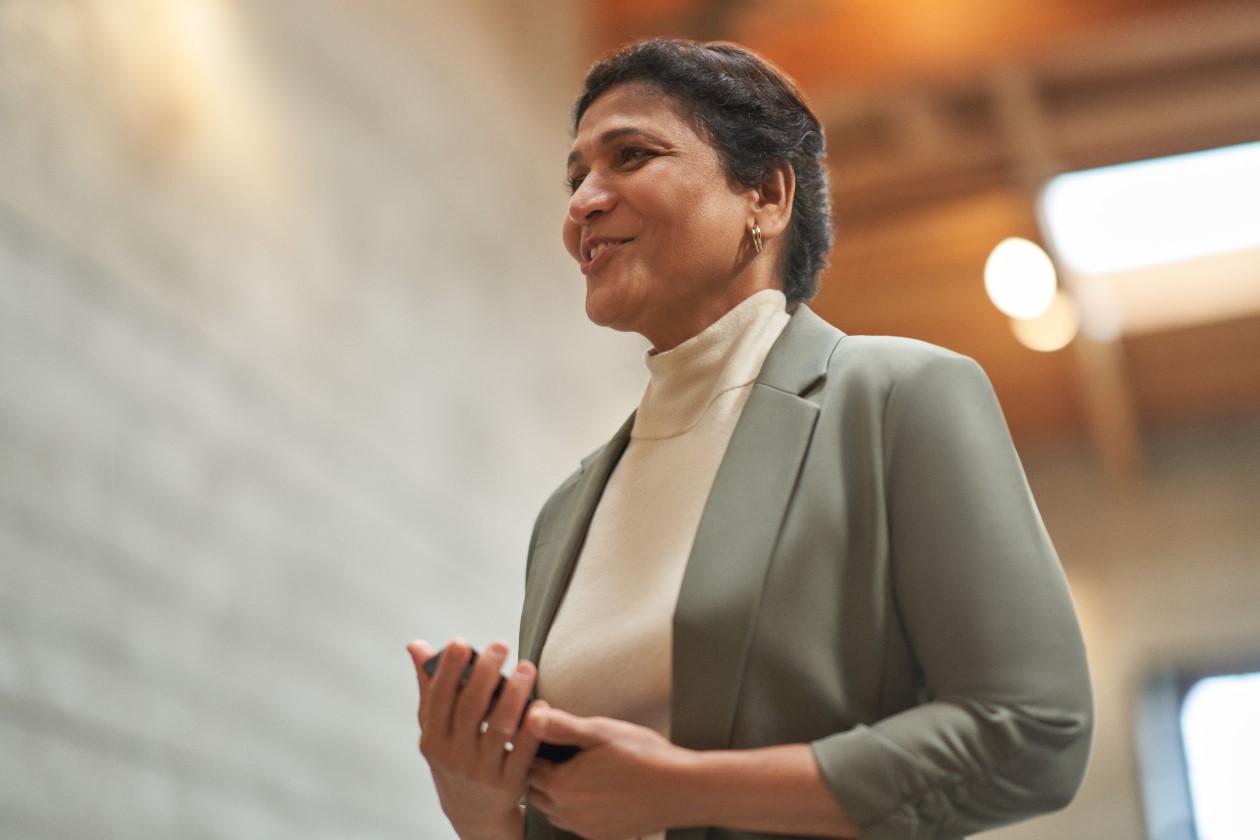 Decorative. An educator standing tall and smiling while looking toward something out of frame
