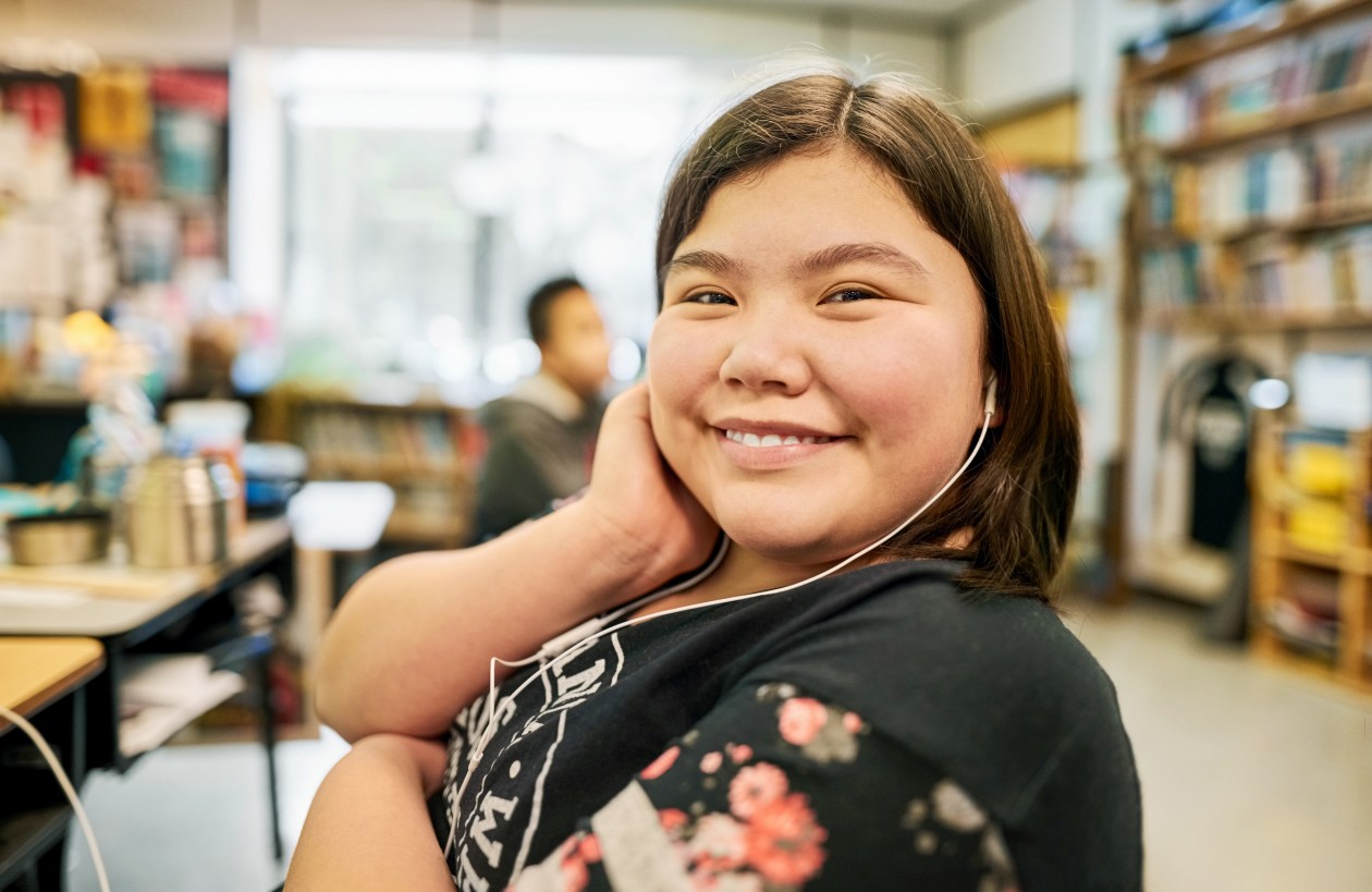 Decorative. A student sits at a desk in a school classroom and faces the camera