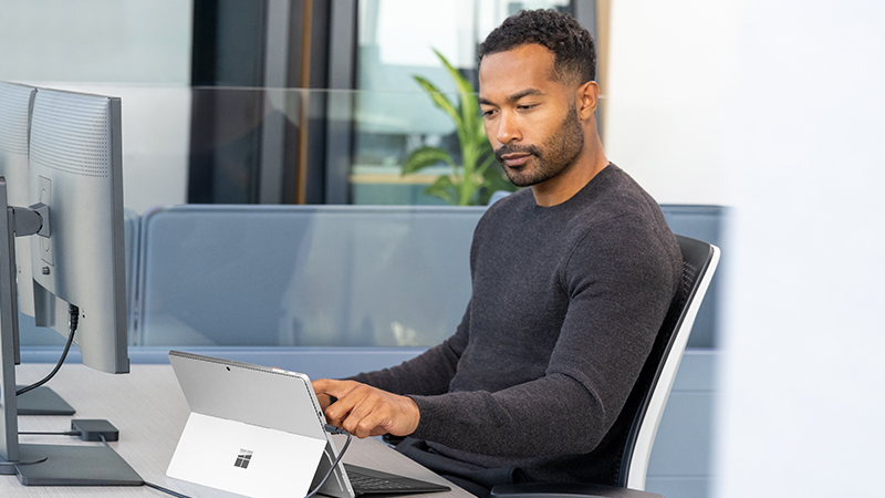 Man sitting in a chair while working on a touch laptop
