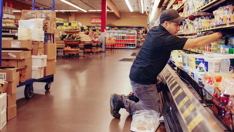Ein Mitarbeiter räumt im Supermarkt Kühlregale ein.