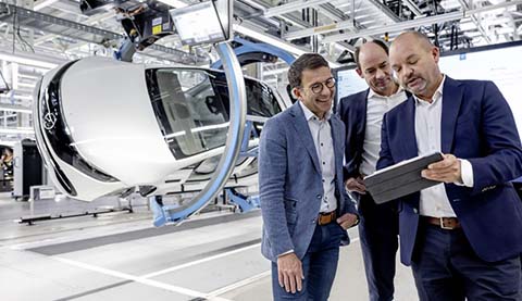 Drei Männer blicken auf ein Tablet bei einem Automobilhersteller.
