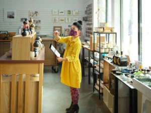 Store manager holding a tablet looking at stock levels. She is wearing a mask. Fraud protection helps manage and protect inventory.