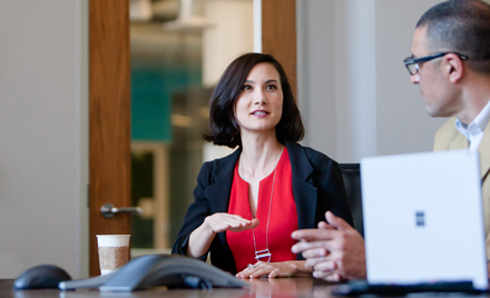 Image of a woman in a meeting, gesticulating as she speaks