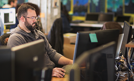 Image of a worker sitting at his computer, concentrating on the screen