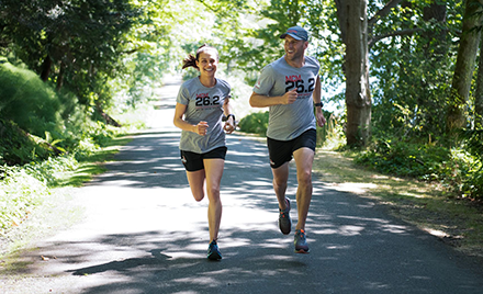 Image of two runners jogging down a forested road