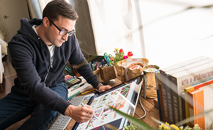 Image of a designer inking with a pen on a large tablet