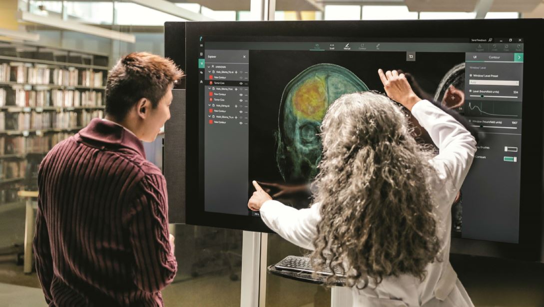 A man and a woman in a library looking at a brain scan