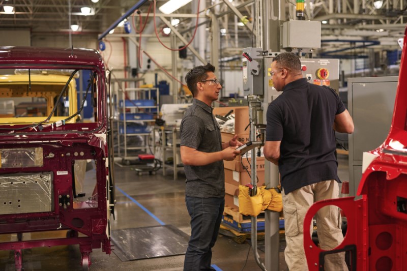 Two engineers wearing safety goggles use machinery at a manufacturing plant