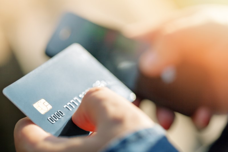 Person transacting with a credit card while using a mobile phone