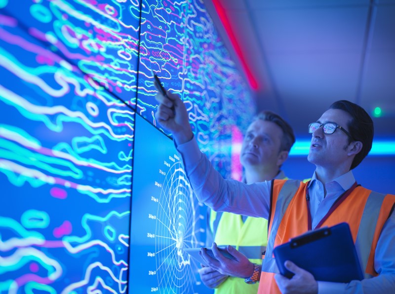 Geologists studying graphical display of oil and gas bearing rock on screens