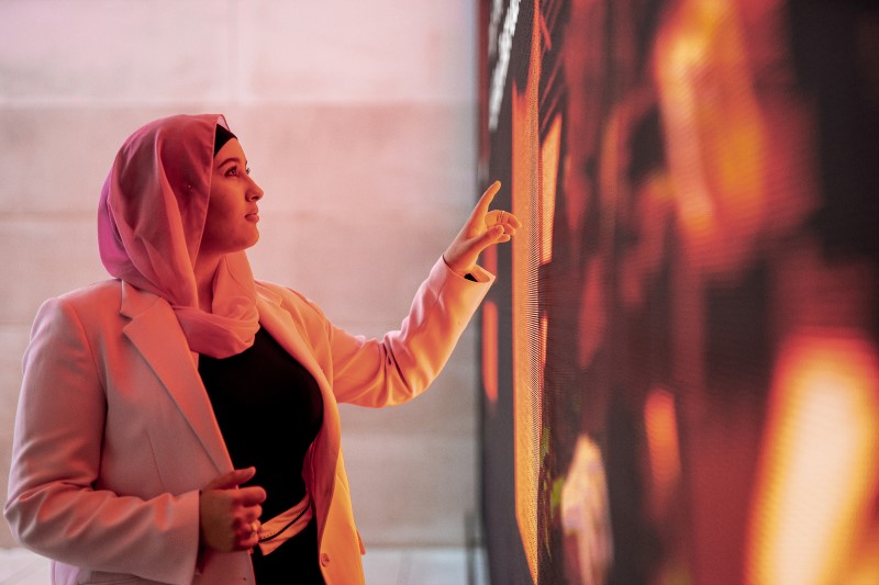 Young woman standing and using a big digital touch screen