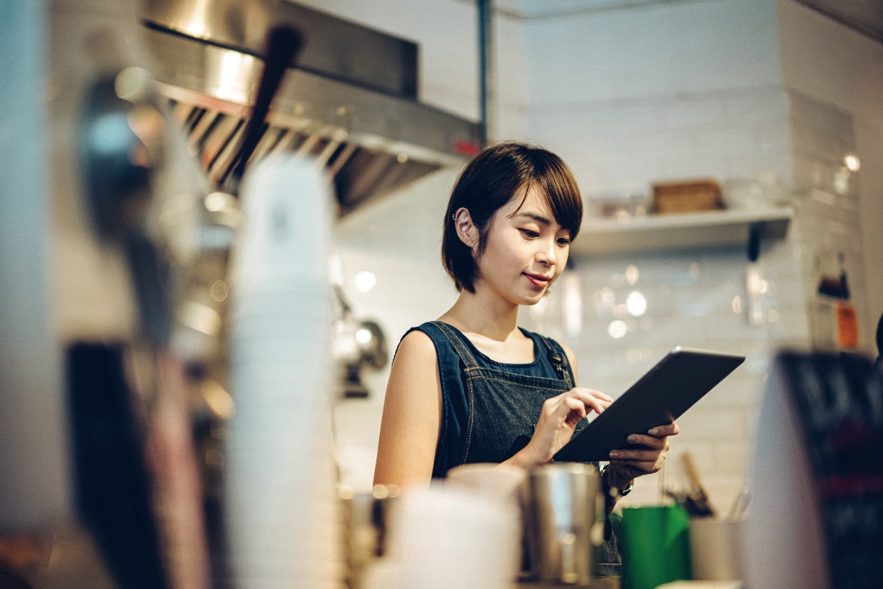 Portrait of a young female barista is using digital tablet in a coffee shop