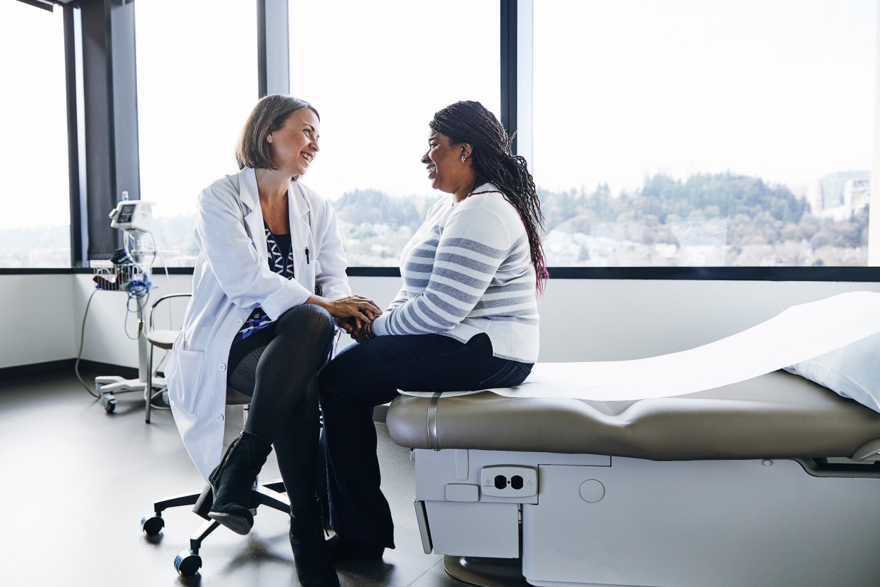 A smiling doctor talks with a woman in a hospital room