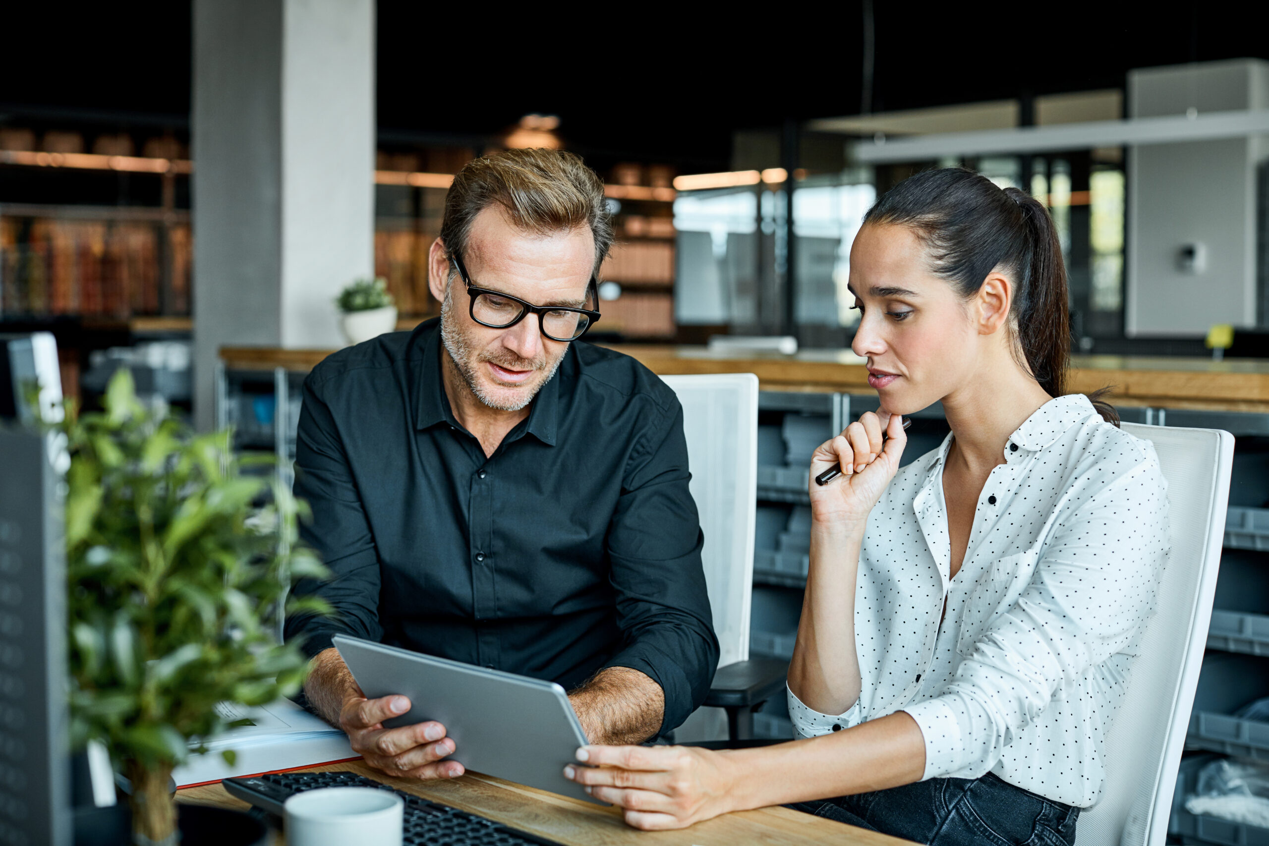 Two business people review documents on a tablet