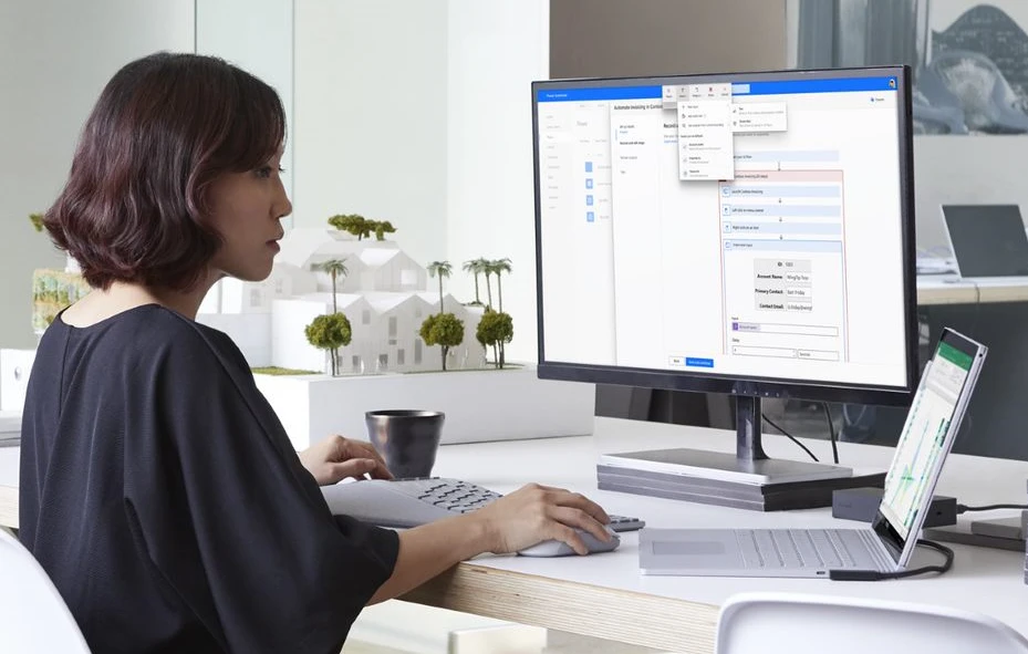 Woman sits at desk using laptop and second monitor