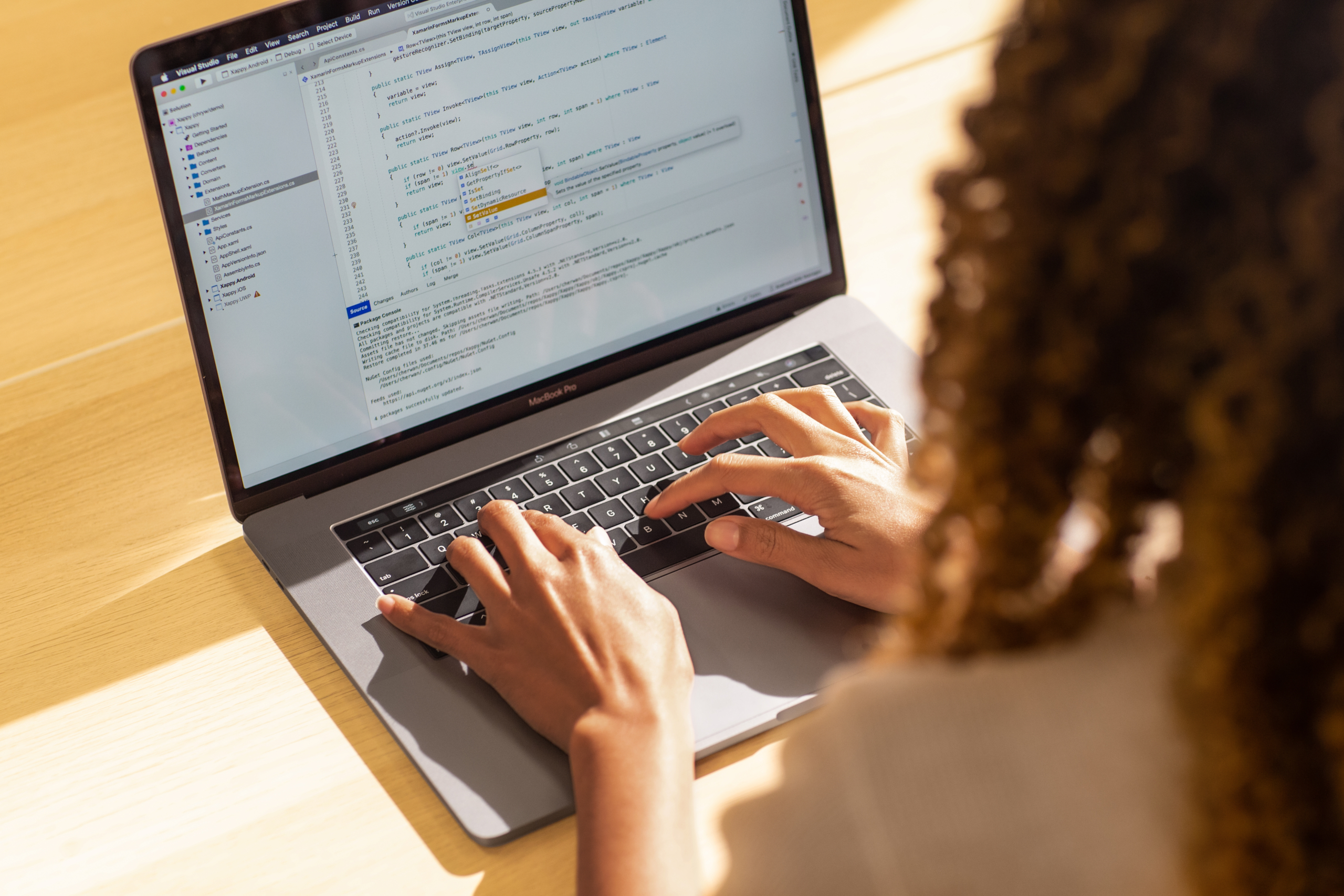 Real people, real offices. Black female developer coding on a MacBook Pro in the office, using Visual Studio. Hands on keyboard. Women who code, women developers, women engineers, code, develop, Black developer, engineer, Visual Studio, Azure