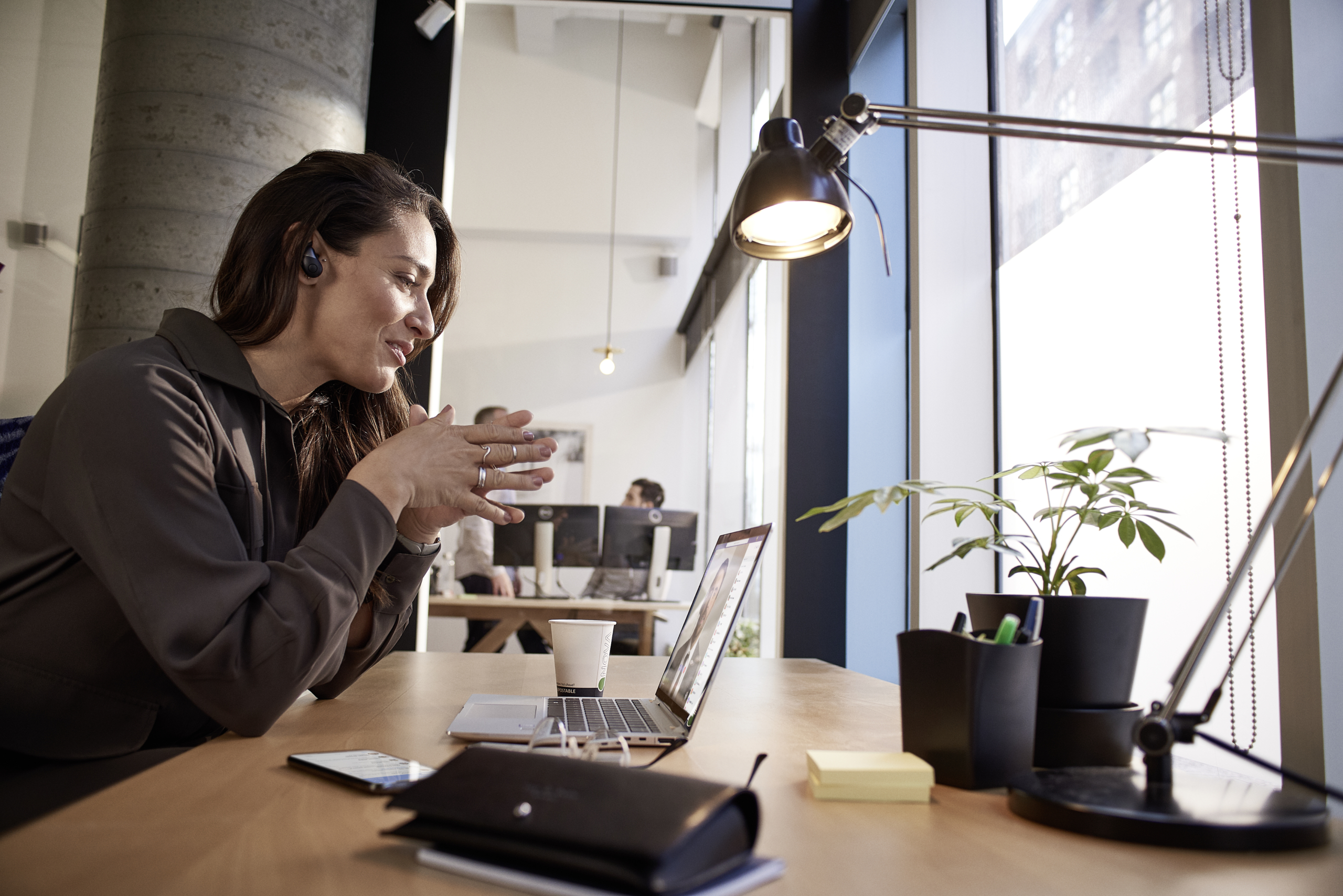 Female small business professional at desk working on an HP Elite Book using Microsoft Teams. Open office