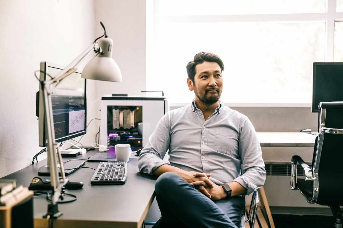 A portrait of programmer sitting at desk in an office
