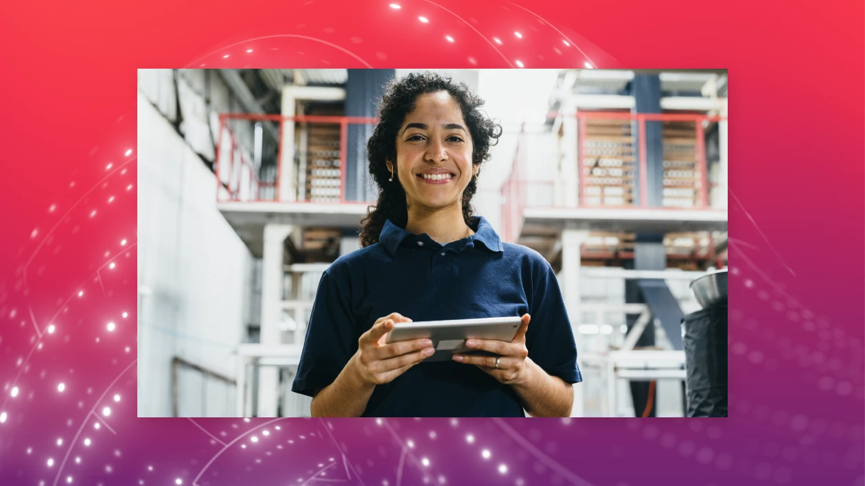A woman stands in a warehouse holding a tablet