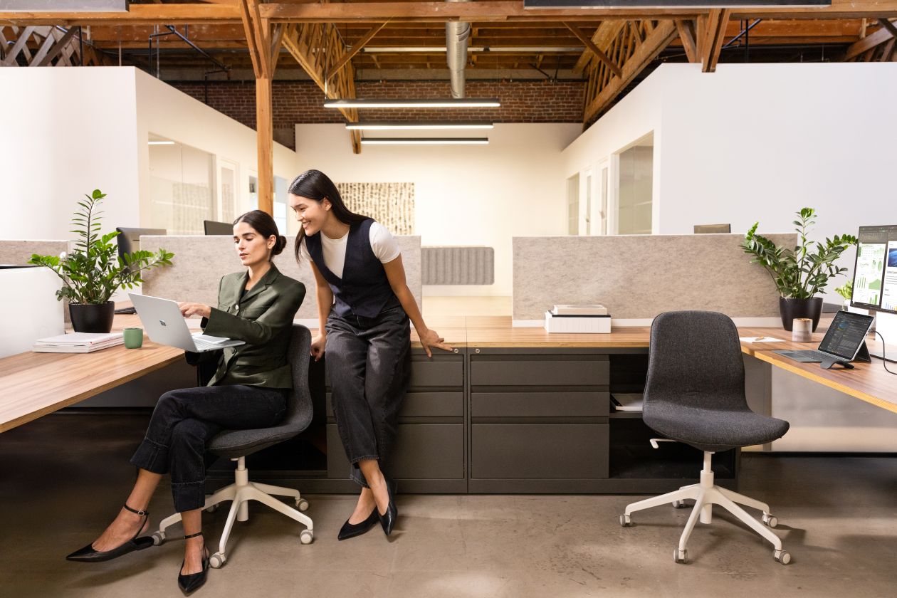 Two coworkers working in cubicle looking at computer monitor