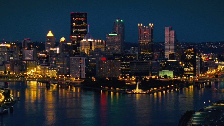 a bridge over a body of water with a city in the background