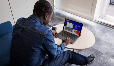 black male sitting at a table working on a laptop