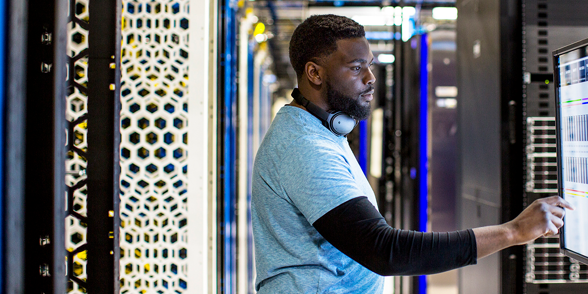Image of a man in a datacenter tapping on a computer screen