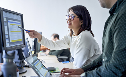 Image of a worker pointing something out to a coworker on her computer screen