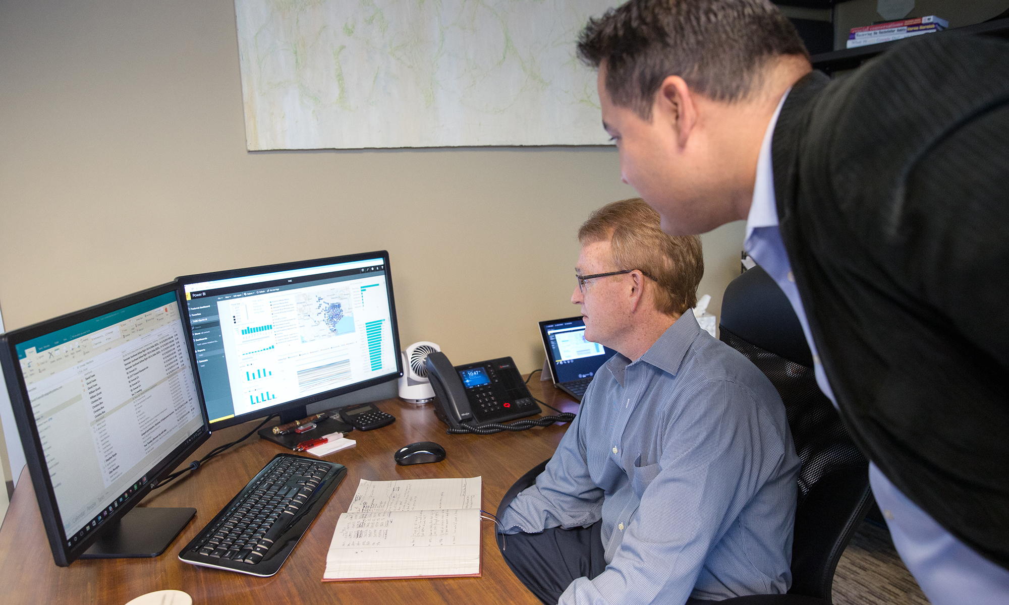 Image of two coworkers looking at computer monitors