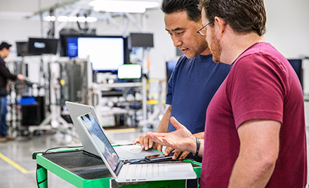 Image of two workers in an office looking at their laptops