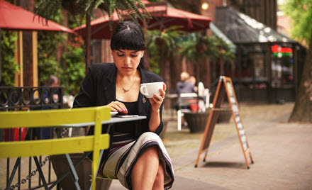 Image of a worker holding a cup of coffee and checking her phone