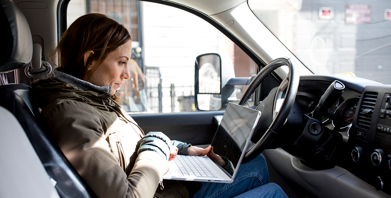 Image of a worker in her car with a laptop