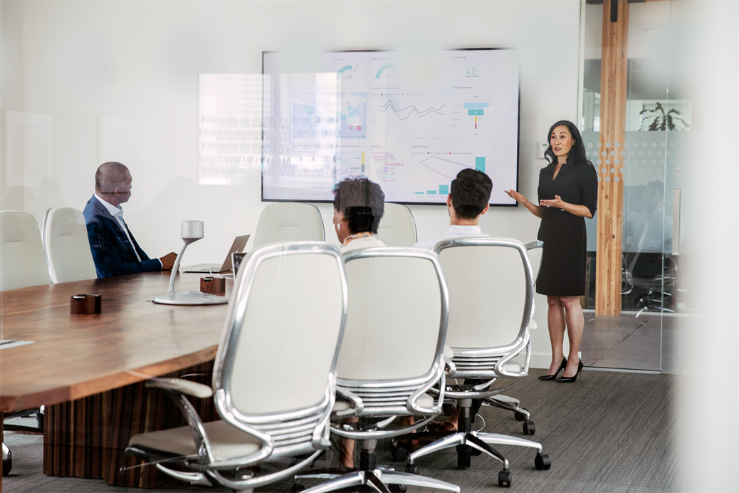 Female executive giving presentation to group in corporate office conference room