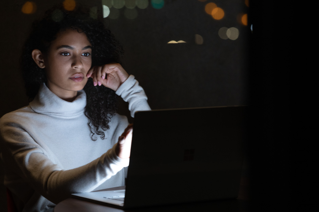 Commercial contextual lifestyle image of adult female working on Surface Book 3 in dark office