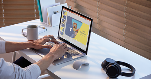 A photograph of Male working on Surface Laptop 3 in PowerPoint with Surface Mouse and Surface Headphones