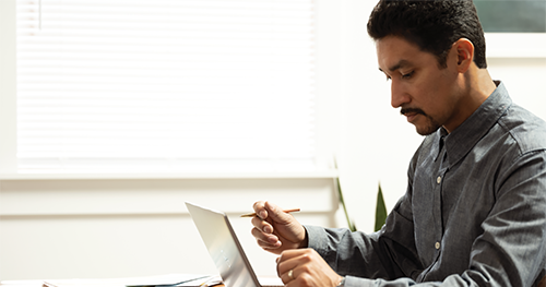 An image of a man working remotely on a Dell Latitude 7410 from his diningroom table