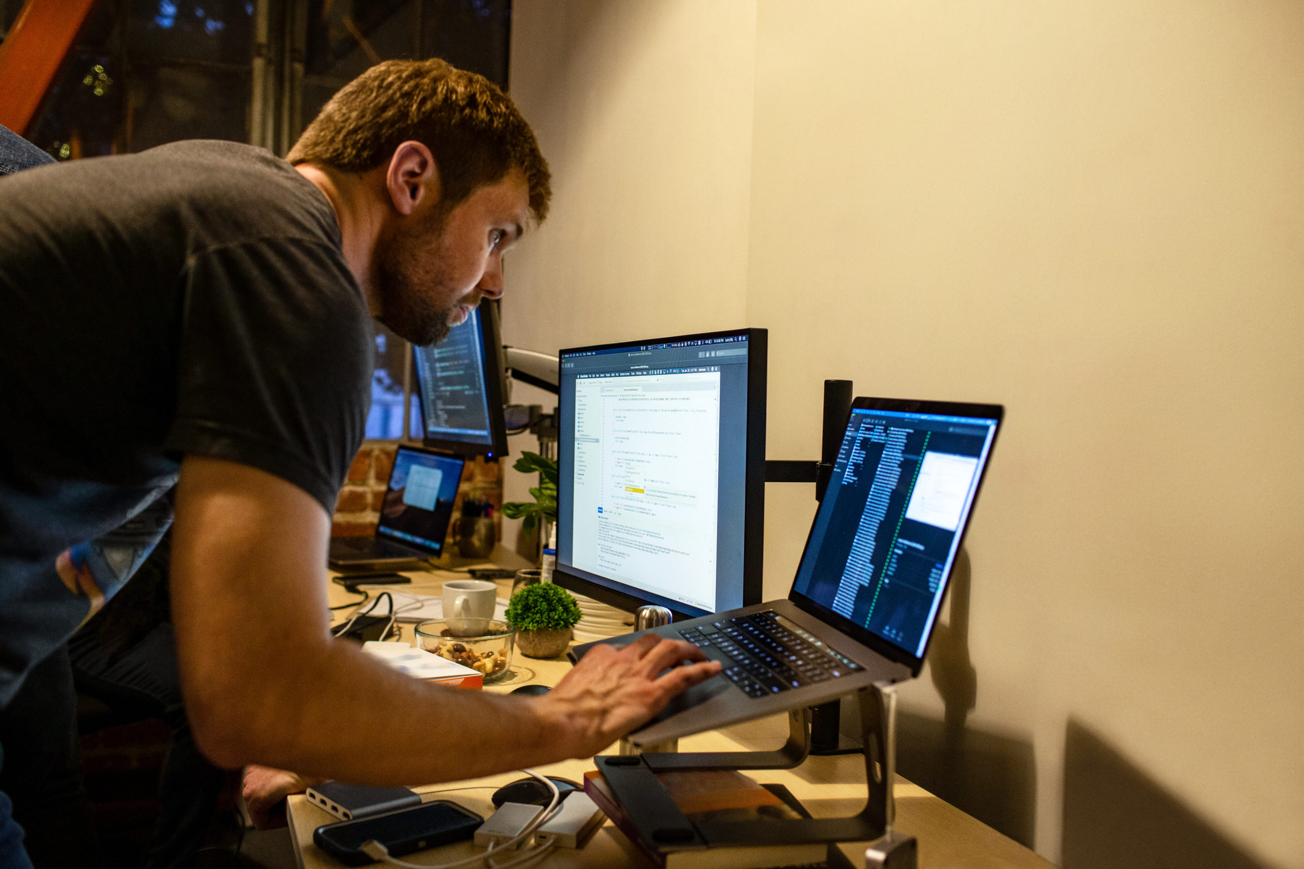 Real people, real offices. Male developer coding while standing at his desk. Code, develop, engineer, Visual Studio, Azure