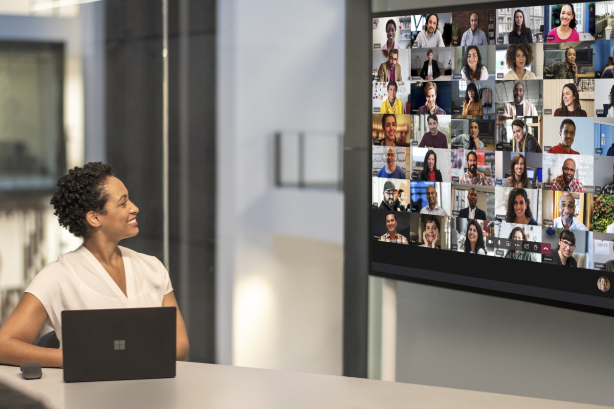 Adult female meeting in a conference room while using Microsoft Teams Together Mode on a Surface Hub 2S 85&rdquo; device