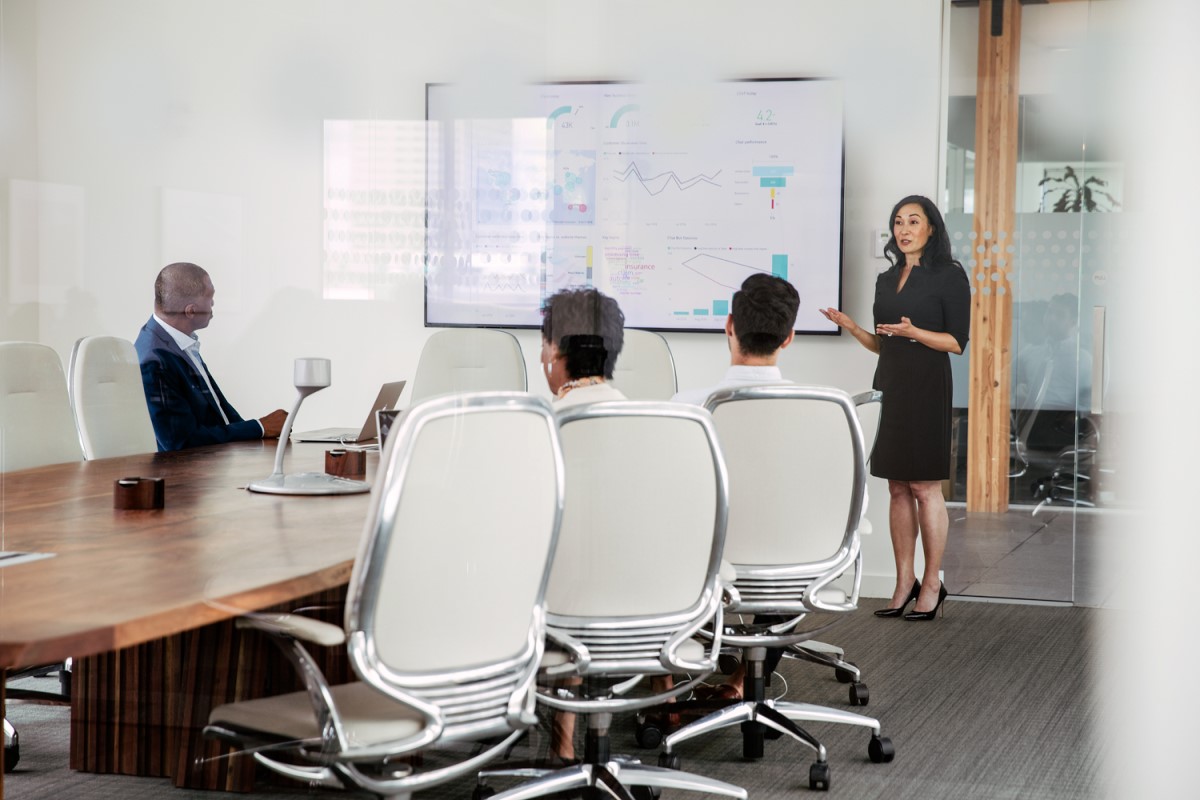 Female executive giving presentation to group in corporate office conference room