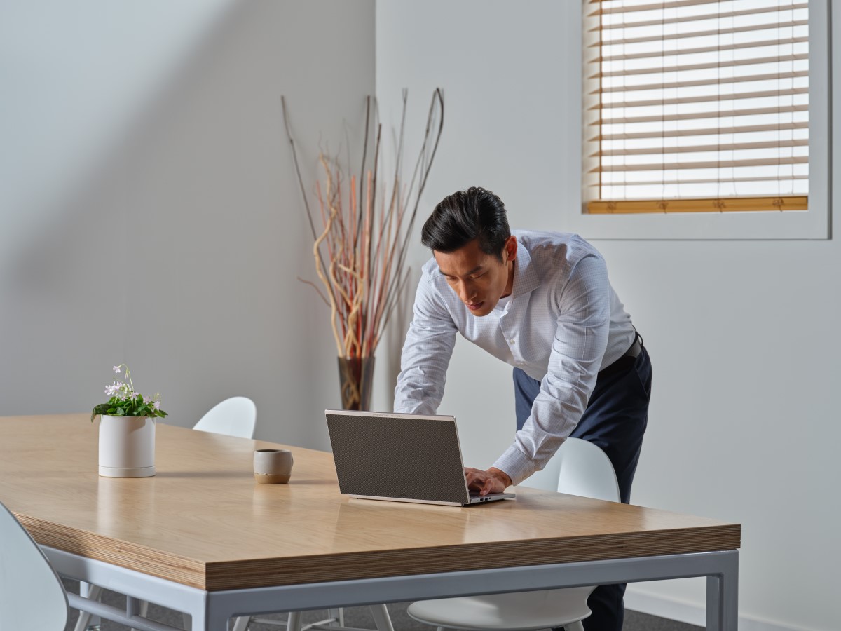 Business person leans over desk to use Acer Porsche RS laptop in a conference room