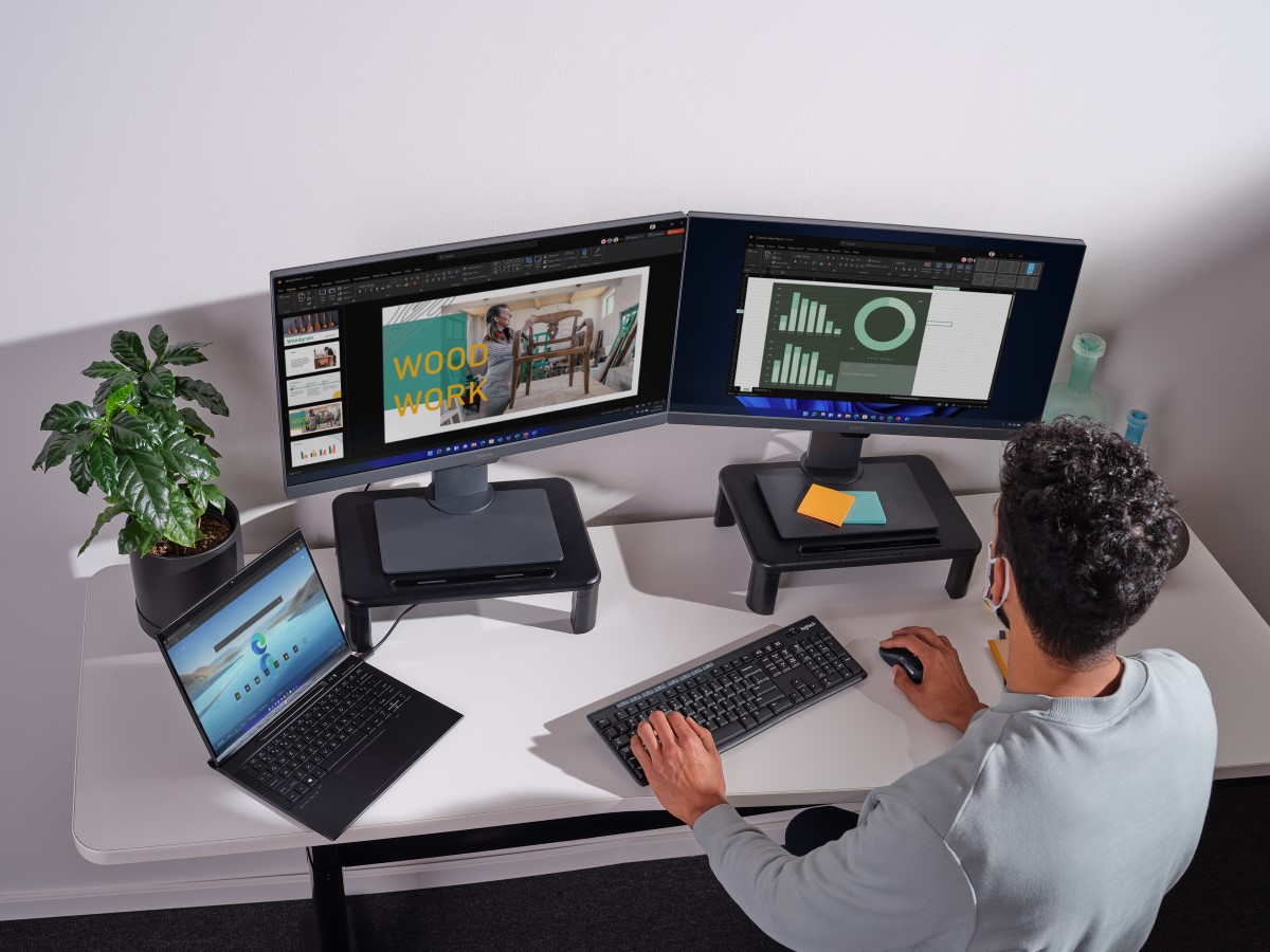 Adult male sitting in home office working on multiple screens