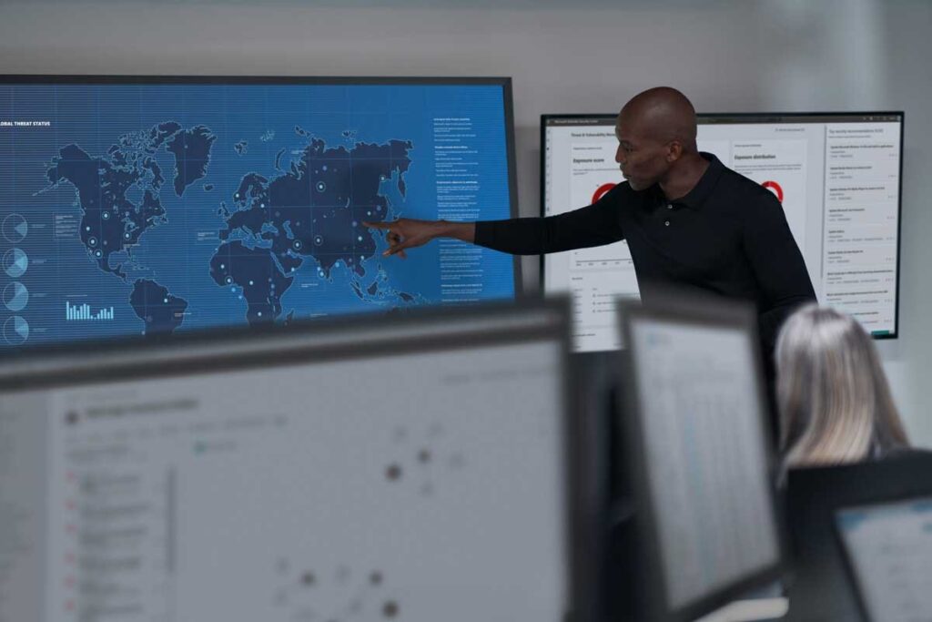 A person pointing to digital map of the world on large screen.