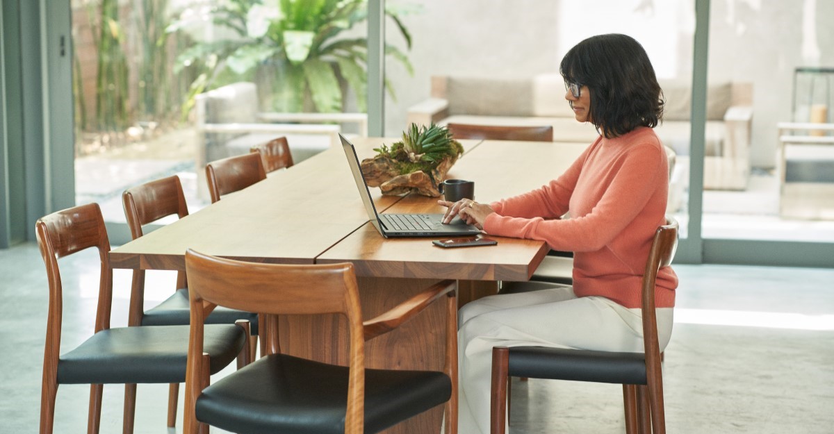 Woman working at dining room table on laptop